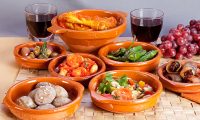 Collection of spanish tapas foods in terracotta bowls.